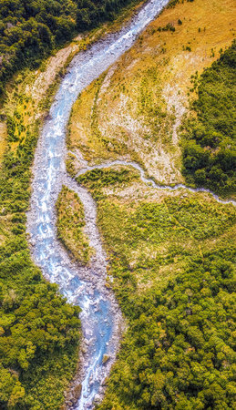 Aerial of green glades, forest and pebbly riverbed at Wilkin river, shot in bright spring light from above, Otago, South Island, New Zealandの写真素材