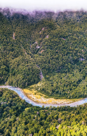 Aerial of green glades, forest and pebbly riverbed at Wilkin river, shot in bright spring light from above, Otago, South Island, New Zealandの写真素材
