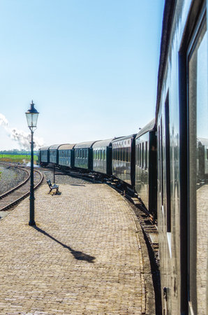Small steam tram locomotive driving through the Dutch countryside, looking out the window view, nostalgic summer tourist attraction in The Netherlandsの写真素材