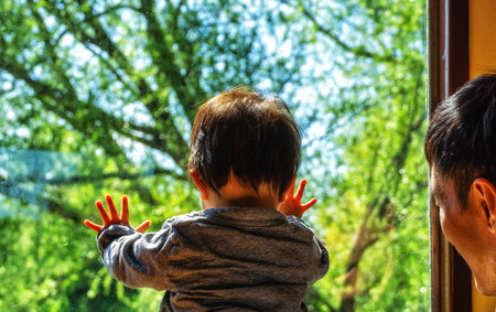 Asian child looks at the rolling landscape view of the Dutch countryside outside the train window while sitting on the seat, The Netherlandsの写真素材