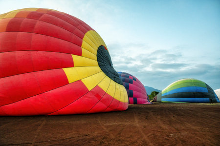 A vibrant hot air balloon in the midst of inflation, set against the serene dawn skyの写真素材