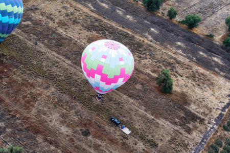 Colorful hot air balloon landing in rural farm fieldの写真素材