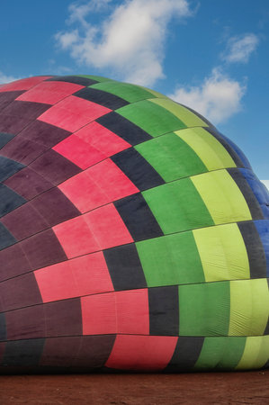 A vibrant hot air balloon in the midst of inflation, set against the serene dawn skyの写真素材