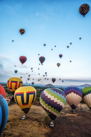 Colorful hot air balloons about to take off at dawn in rural field with blue sky near the town of Teotihuacan, Mexico.の写真素材
