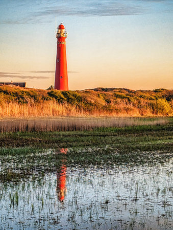 Schiermonnikoog  view in the dunes with the lighthouse during sunset at the wadden island during a beautiful spring day. Schiermonnikoog is part of the Frisian Wadden Islands and is known for its beautiful natural scenery, including sandy beaches, rolling dunes, and lush wetlands.の写真素材