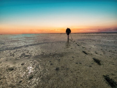Walking on mud flats and tideway at low tide of Wadden Sea near Schiermonnikoog, Netherlandsの写真素材