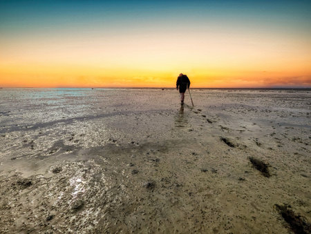 Walking on mud flats and tideway at low tide of Wadden Sea near Schiermonnikoog, Netherlandsの写真素材