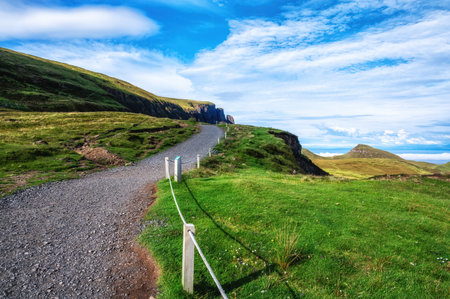 Hiking path leading to rock formation on sunny day at Quiraing, Isle of Skye, Scotland