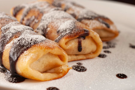 Pancakes with chocolate and sugar on a white plateの写真素材