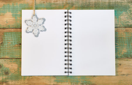 snowflake on a white page of an open notebook on a wooden background.の写真素材