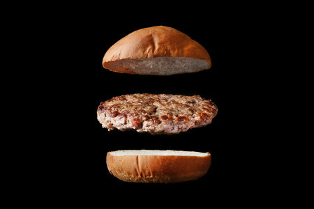 fly burger isolated on black background. bun and meatの写真素材