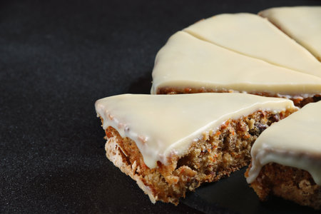 carrot cake with icing on dark background close up