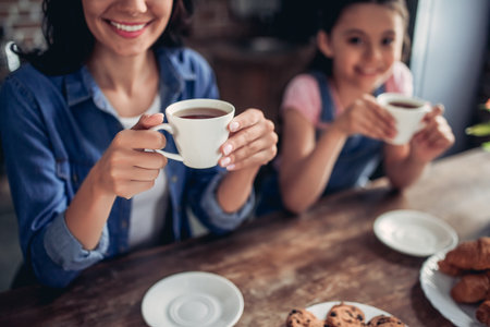 cropped shot of mother and daughter drinking tea together in the kitchenの写真素材