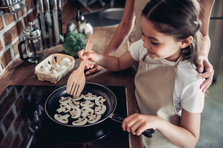 cropped shot of daughter and mother frying mushrooms on the stove together for dinner at the kitchenの写真素材