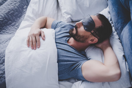 Portrait of handsome man in sleeping mask lying in bedの写真素材