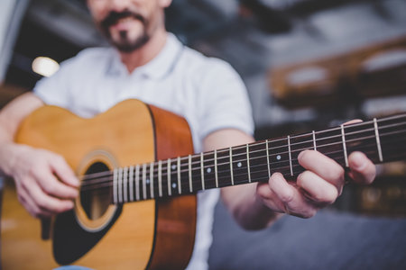 close up of man playing guitar at homeの写真素材