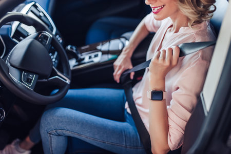 cropped shot of caucasian woman fastening safety belt in the carの写真素材