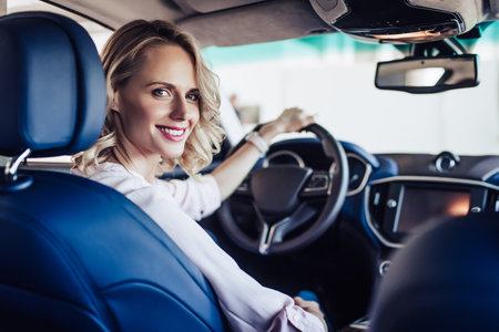portrait of young smiling woman sitting in the car and looking at the cameraの写真素材
