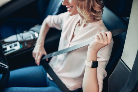 cropped shot of smiling woman fastening safety belt in the carの写真素材