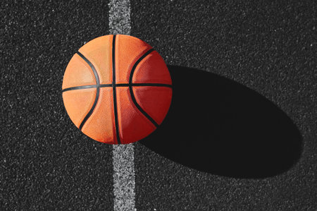 No people photo of a classy basketball laying on a dark asphalt in the sunlightの写真素材