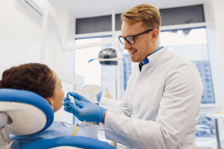 Smiling doctor and female patient choosing teeth color with palette. medical treatment processの写真素材