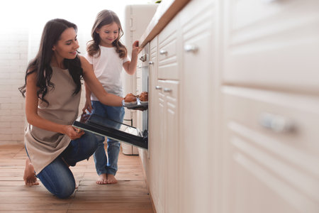 cheerful girl with mother prepared muffins at homeの写真素材