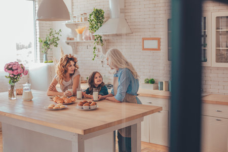 three generations family talking on the kitchen with milk and cookiesの写真素材