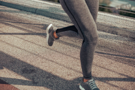 cropped shot of woman in sport wear running on the bridge in the cityの写真素材