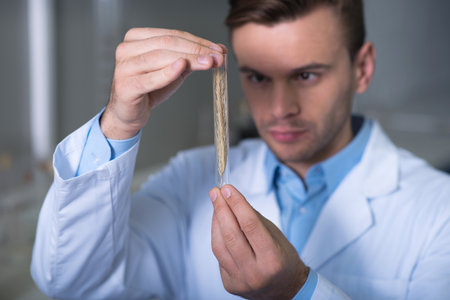 Product of research. Perspective serious concentrated scientist in a uniform standing in the room...