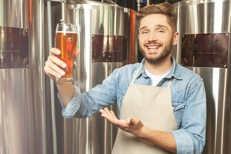 smiling brewmaster expert checking the quality of the freshly tapped beer