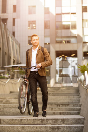Handsome man expressing confidence while bringing his bicycle downstairs