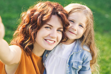 portrait of cute girl with curly hair with mother looking at the camera