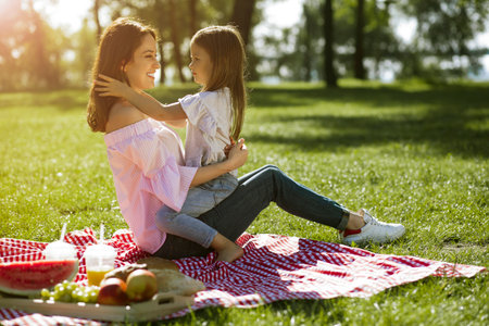 small girl sitting on mother laps in the park small girl sitting on mother laps in the parkの写真素材