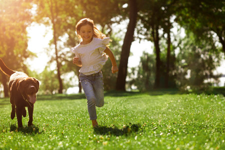 full length shot of little girl running in the park with her dogの写真素材
