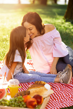 girl and woman at picnic in the park touching nose to noseの写真素材