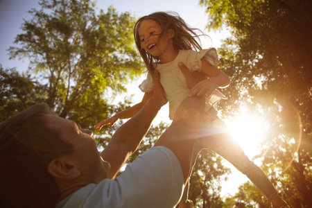 father holding small daughter up on the hands in the parkの写真素材
