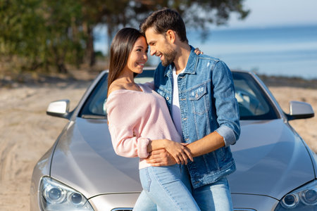 side view of man and woman hugging together at the car outdoorsの写真素材