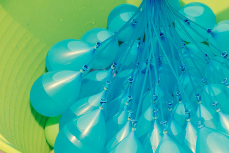 Blue water balloons being filled up in a green tub.の写真素材