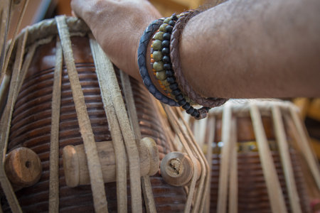 Images of a man's hands (wearing beads) playing the Tabla - Indian classical music percussion instrument - black background.の写真素材