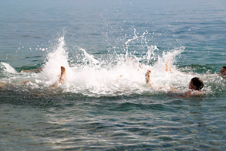 Group of children upside down splashing in the sea.の写真素材