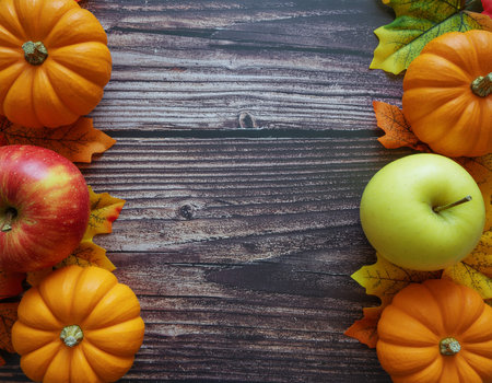 Cozy autumn holiday background featuring mini pumpkins, red and green apples, and colorful fall leaves on rustic wooden planks. Perfect seasonal backdrop for Thanksgiving, harvest celebrations, and fall-themed designsの素材