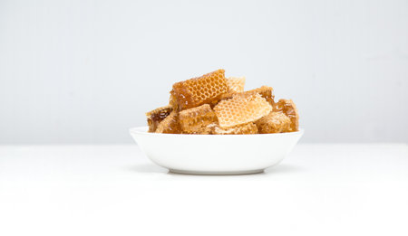 Pieces of honeycombs in a bowl. Fresh bee honey in honeycomb pieces on white background.の写真素材