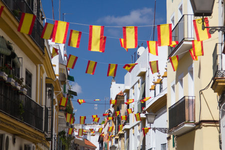 Spanish flags on the street in Seville, Spain. Details of old buildings facade, wall with wooden frame windows.の写真素材