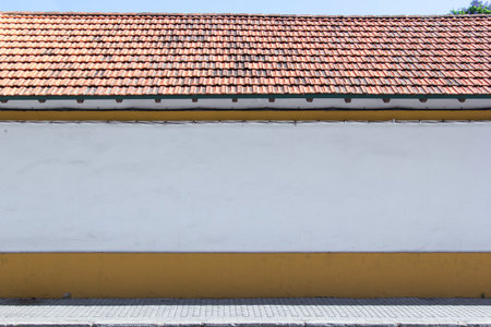 Blank, white wall by the street - clean space as a background for a graphical mockup. Orange tile roof.の写真素材
