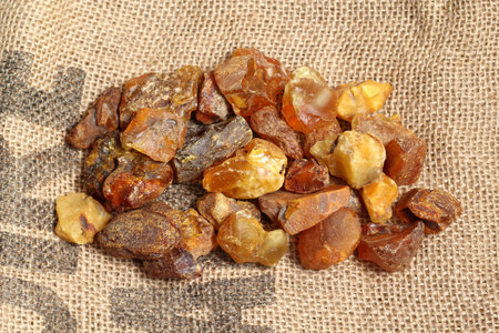 Natural raw amber stones on jute bag background. Multiple amber gemstone in various shapes and color. Jewelry components.の写真素材