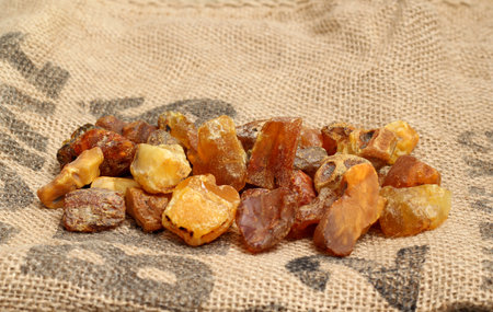 Natural raw amber stones on jute bag background. Multiple amber gemstone in various shapes and color. Jewelry components.の写真素材
