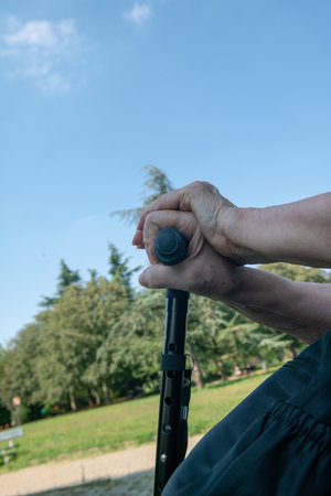 elderly person with cane, leg support with the cane useful for walking in the park, walking problems, arthrosis.の写真素材