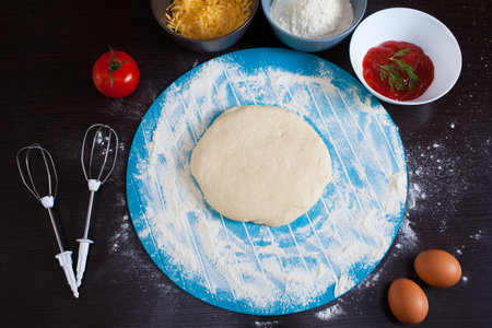 Pizza cooking ingredients. Raw pizza ingredients - dough, sauce, cheese, tomato, flour, eggs.の写真素材