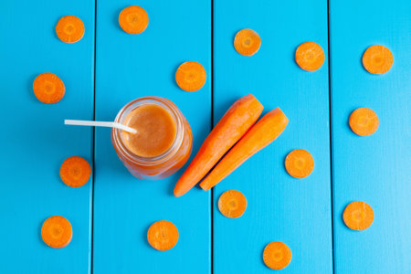 Healthy carrot smoothie in a jar on blue wooden background. Top view.の写真素材