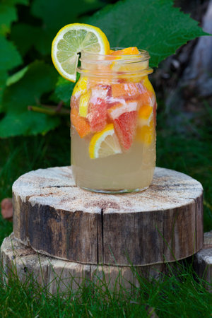 Fresh lemonade from lemon and grapefruit in a jar on a wooden stump. Outdoorsの写真素材